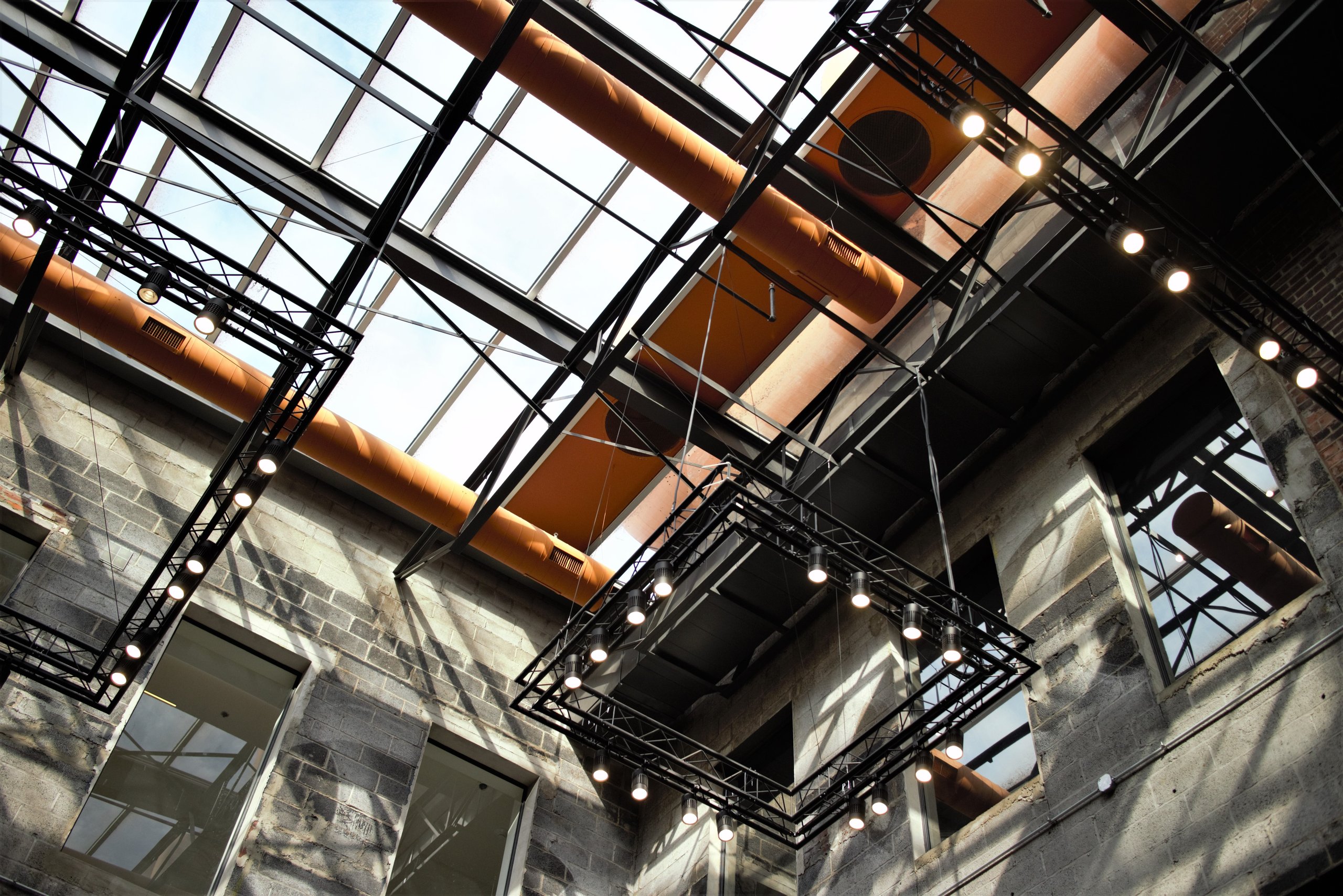 The atrium ceiling at Billy Penn Studios — steel truss and skylight over a restored factory floor
