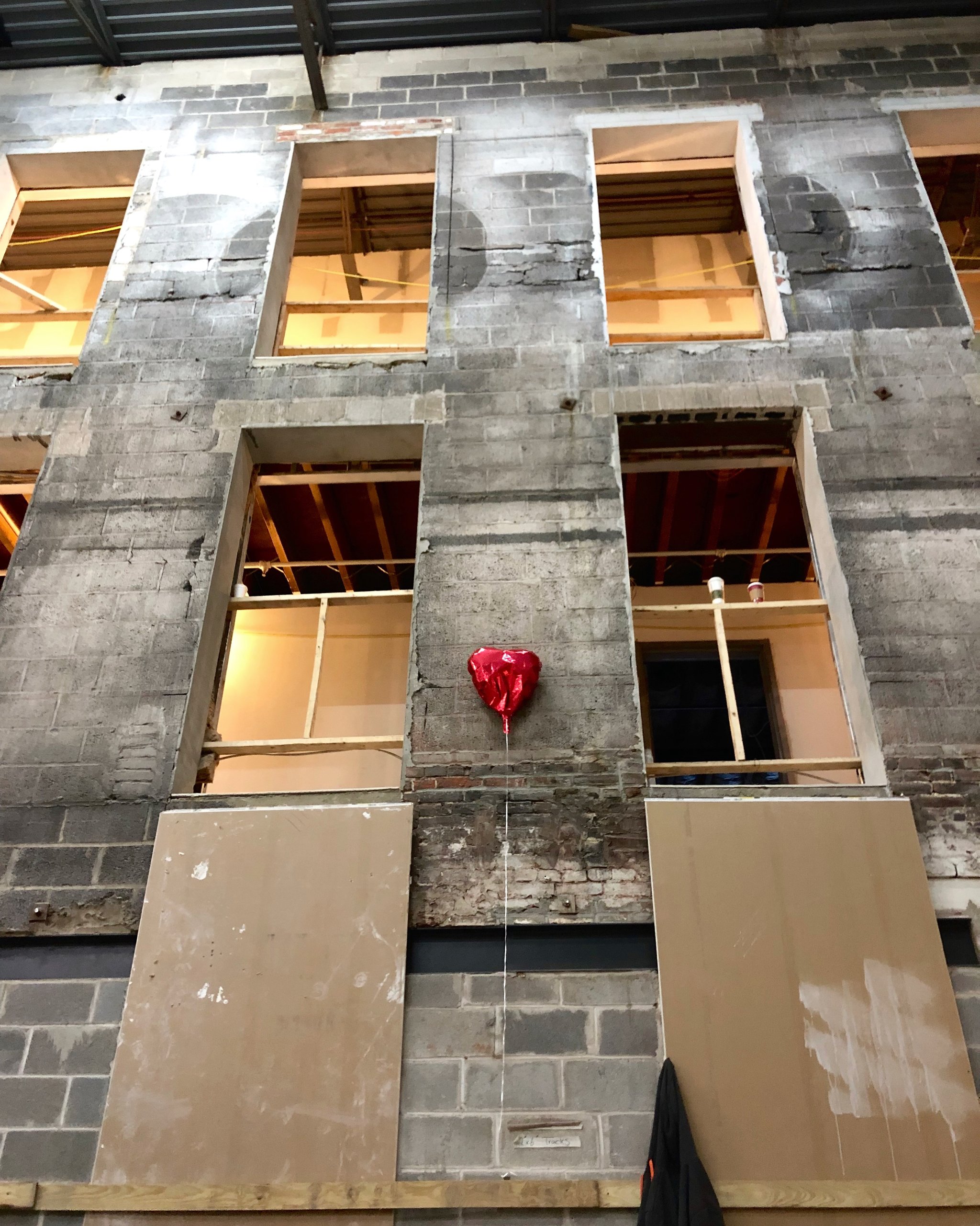 A red heart balloon on the atrium wall at Billy Penn Studios during construction