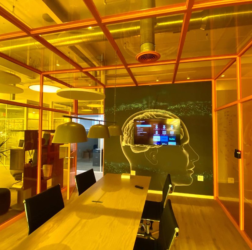 A conference room at Billy Penn Studios seen through the amber tinted glass of its enclosure
