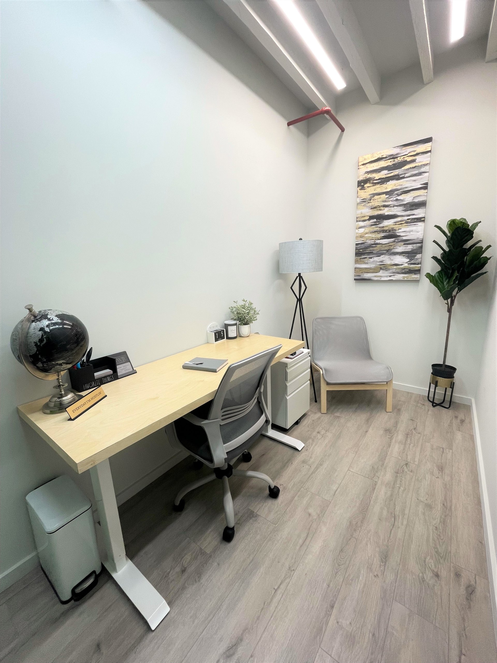 A one person private office at Billy Penn Studios with a standing desk, task chair, filing cabinet and an armchair in the corner