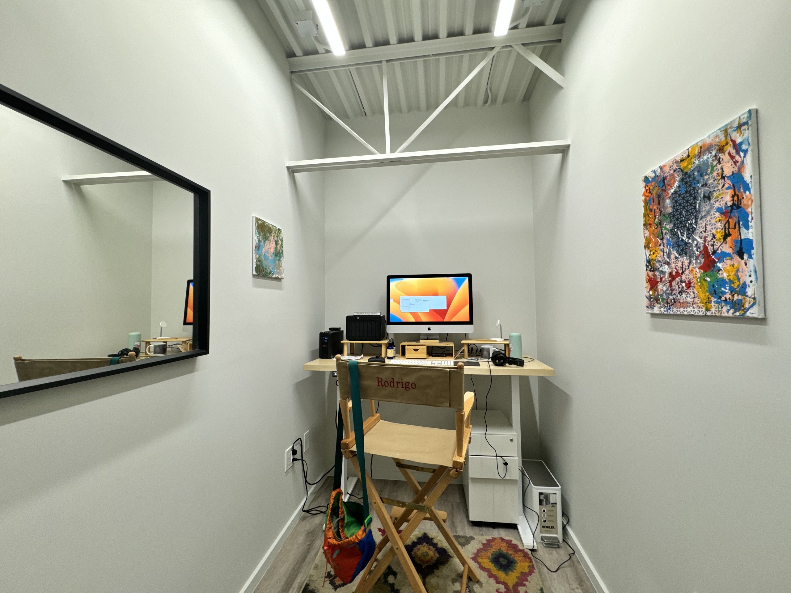 Another one person private office at Billy Penn Studios, with a desk under a white painted truss and the tenant's own artwork on the walls