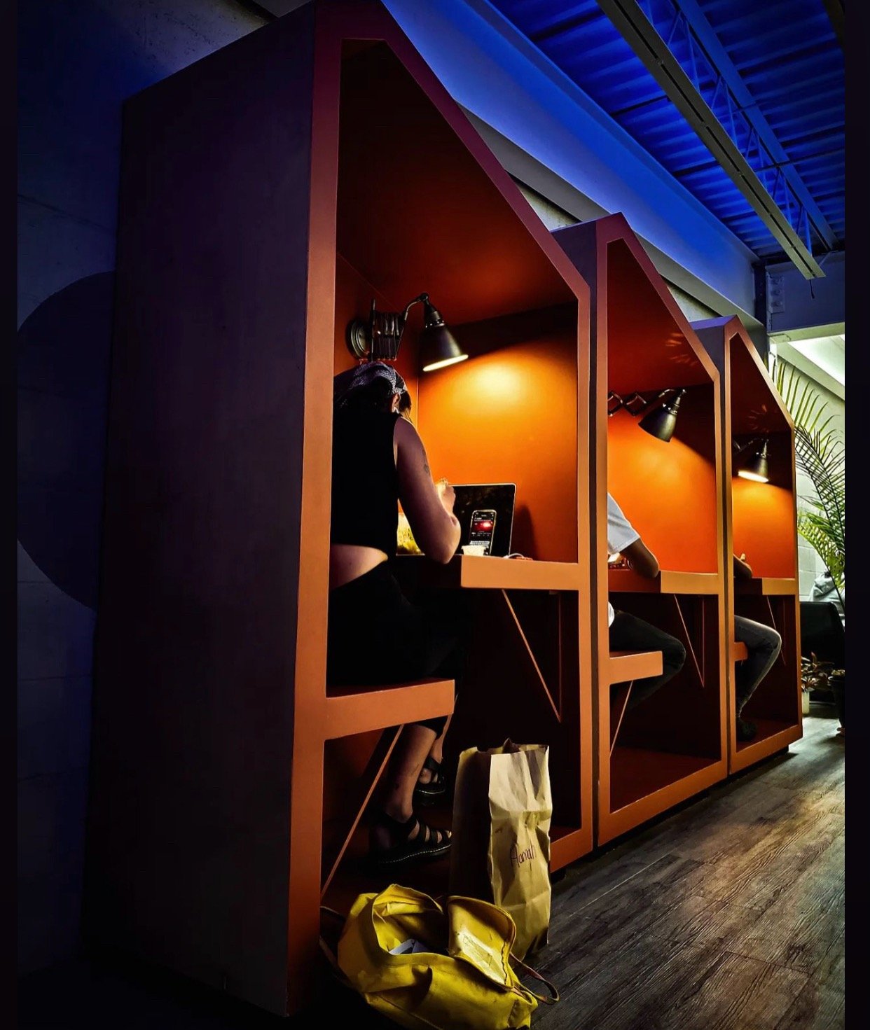 A member working head down in one of the orange built-in booths at Billy Penn Studios coworking