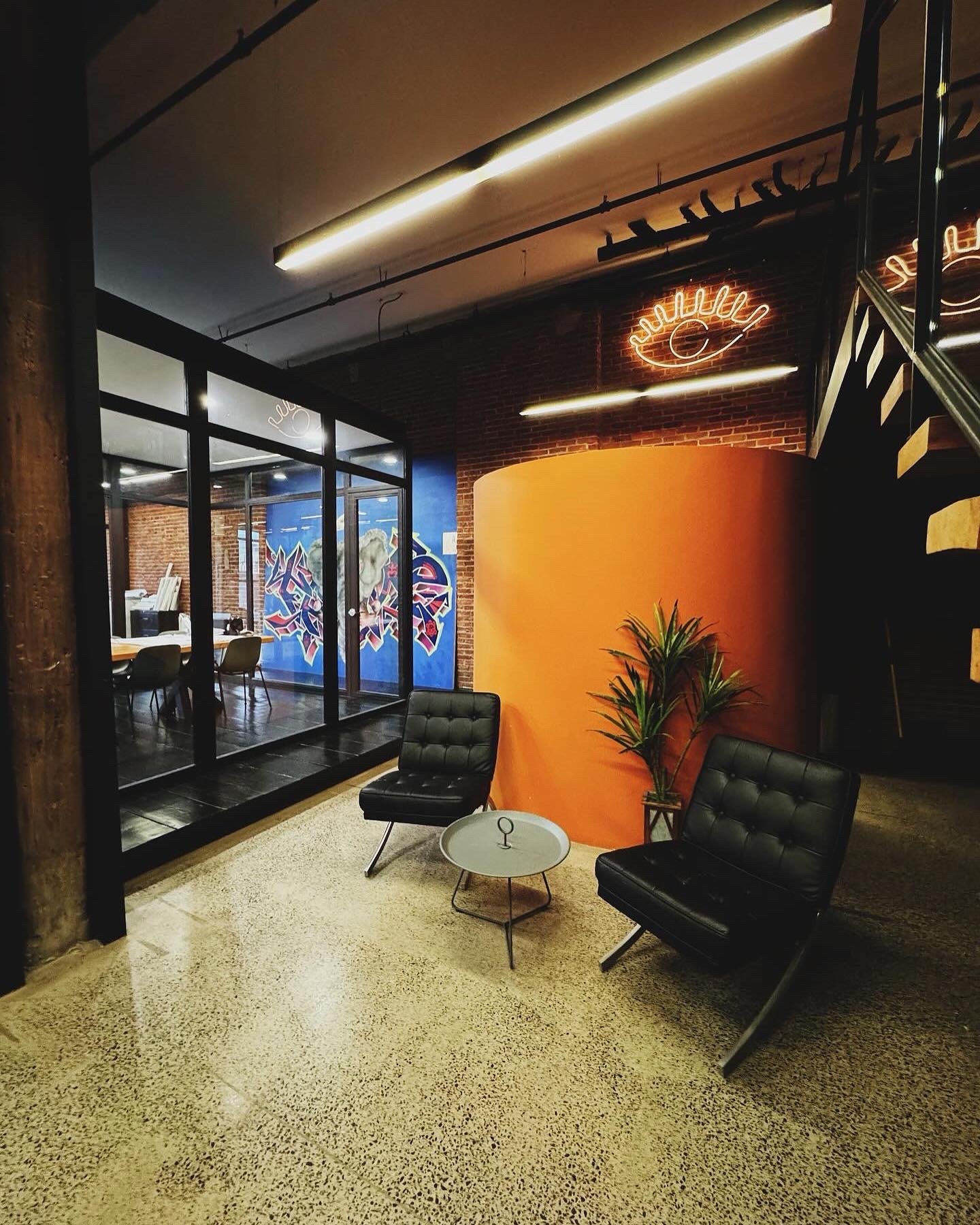 Steel framed glass partitions at Billy Penn Studios, beside a curved orange wall, neon sign and graffiti mural