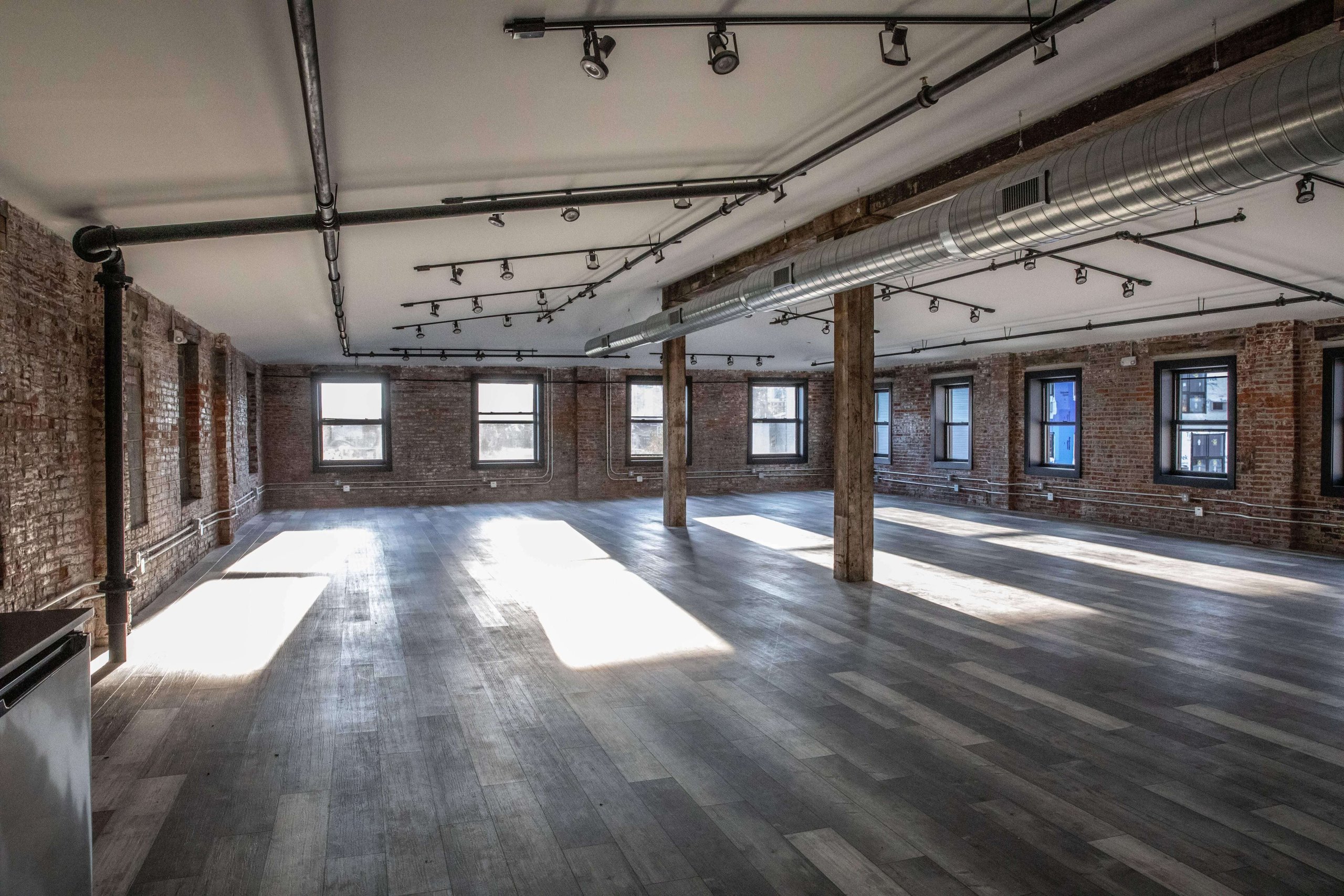 Unit 504 at Billy Penn Studios — an open office with exposed brick, timber posts and factory windows