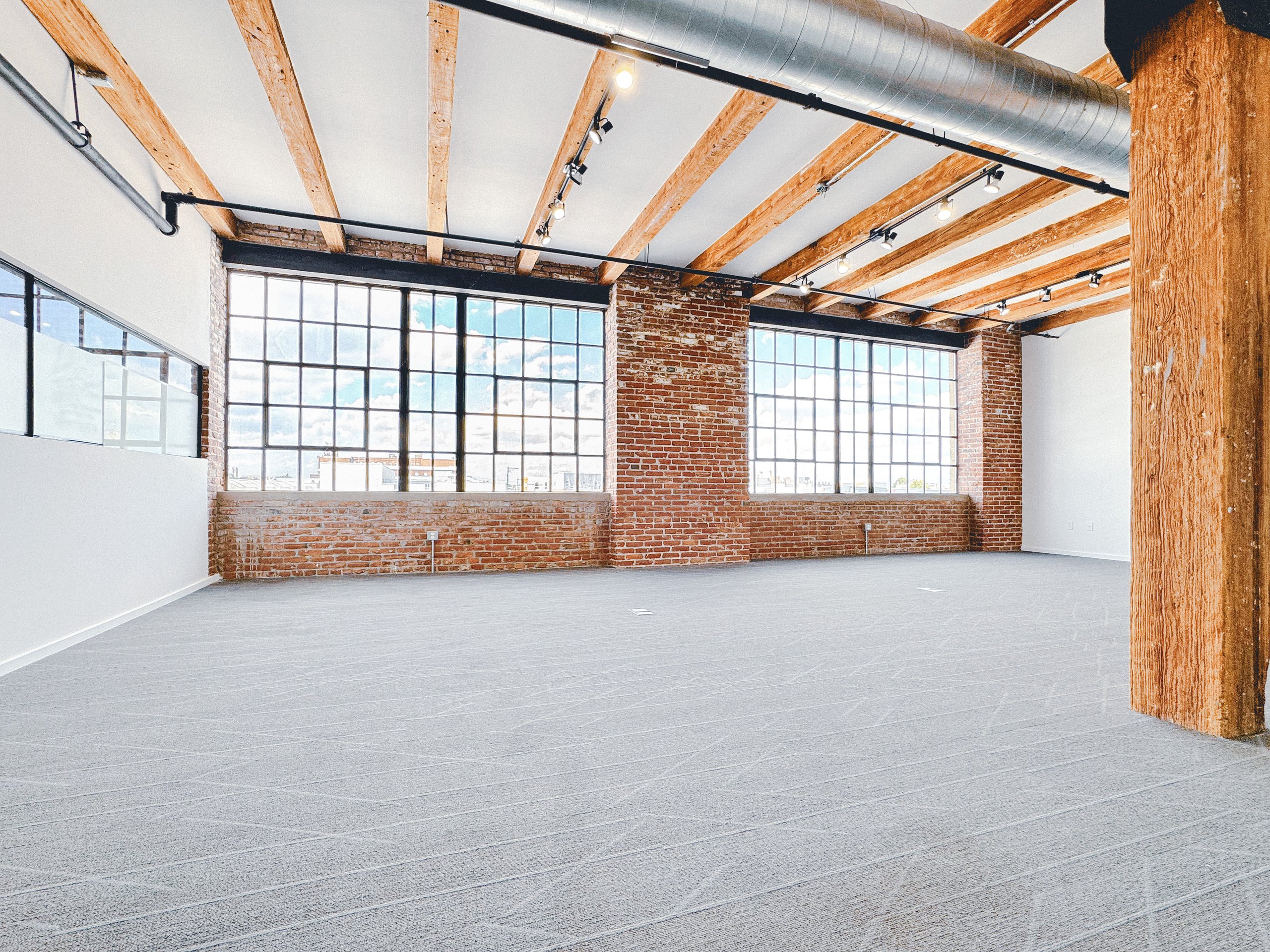 Restored black framed multi-pane factory windows above exposed brick sills at Billy Penn Studios